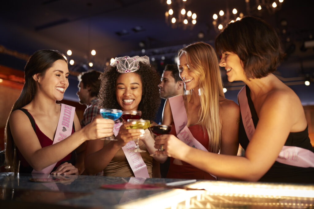 Group of female friends celebrating with the bride on a hen party in a bar