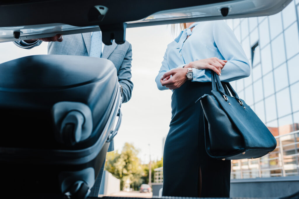 Businessman loading luggage into luxury vehicle with colleague nearby